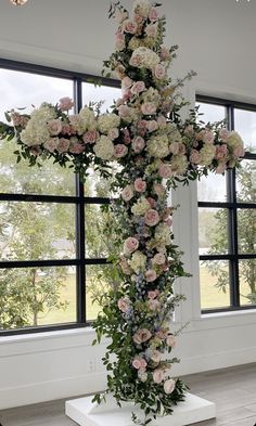 a cross made out of flowers in front of a window