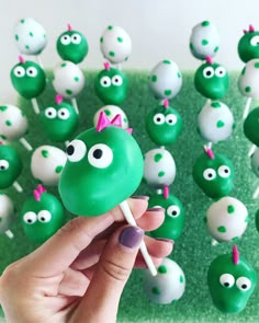 a hand holding a lollipop in front of green and white candies with googly eyes on them