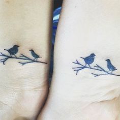 two small birds sitting on top of each other's wrist tattoos, one is blue and the other is black