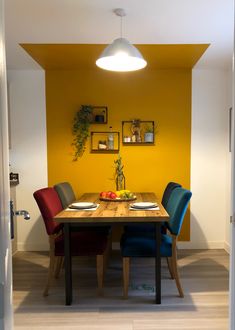 a dining room with yellow walls and blue upholstered chairs around a wooden table