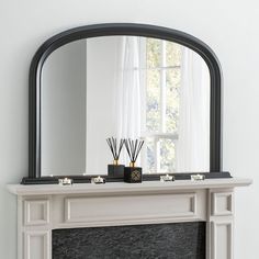 a fireplace with a mirror and candles on it