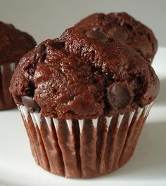 two chocolate muffins sitting on top of a white plate next to each other