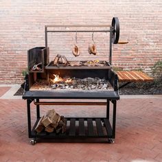 a bbq grill with wood and fire on the side walk next to a brick wall