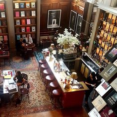 people sitting at tables in a library with bookshelves and wine bottles on the walls