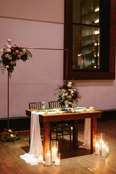 a table with candles and flowers on it in the middle of a wooden floored room