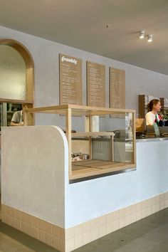 a woman standing in front of a counter at a restaurant with menus on the wall