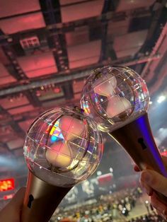 two disco balls being held up in front of an audience