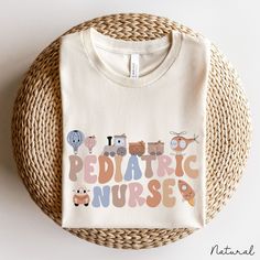 a white t - shirt with the words pediatric nurse printed on it sitting next to a wicker basket