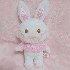 a white stuffed animal with brown eyes on a pink background