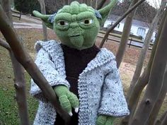 a knitted yoda doll sitting in a tree