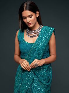 Feeling blue? Don’t worry, we’ve got you covered. Presenting to you our Teal blue georgette sequinned saree. The only blue that’ll make you not just happy but also look super stylish. This piece comes with an unstitched blouse. The saree itself is an easy pick and a key garment for all your events. Order yours now and get ready to be a show-topper. Standard and Customized blouse stitching available for an additional fee. Please note this blouse can be stitched up to a size 44, and cannot be made Blue Sequined Pre-draped Saree For Party, Blue Embellished Saree For Navratri, Blue Pre-draped Saree With Cutdana For Party, Blue Cutdana Pre-draped Saree For Party, Festive Blue Pre-draped Saree With Sequins, Blue Sequined Party Wear Saree, Traditional Blue Pre-draped Saree With Sequins, Traditional Blue Sequined Pre-draped Saree, Blue Mirror Work Blouse Piece For Party