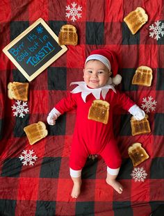 a baby dressed as the elf is laying on a blanket with toast and marshmallows