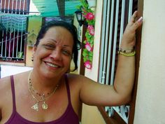 a woman is smiling and holding her arm up in the air while standing next to a building