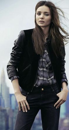 a young woman standing in front of a cityscape with her hair blowing in the wind