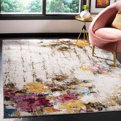 a living room area with a pink chair, rug and large window overlooking the trees