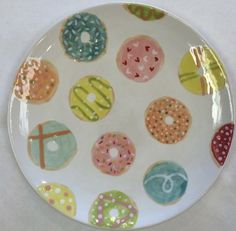 a plate with donuts painted on it sitting on a white tableclothed surface