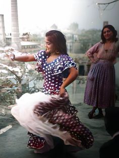 a woman in a dress is dancing with her arms out and two other women are standing behind her