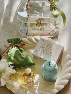 an assortment of personal care items on a tray with a green satin bag and white flowers