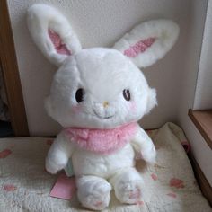 a white stuffed rabbit sitting on top of a bed