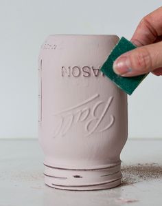 a hand holding a green sponge over a white cup with the word rosv on it