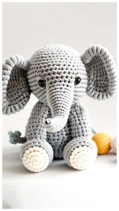 a crocheted elephant sitting next to a ball of yarn