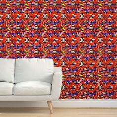 a white couch sitting in front of a wall covered in red, blue and yellow shapes