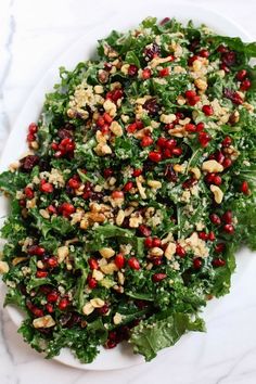 a white plate topped with lettuce and pomegranate covered in nuts