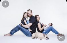 a man, woman and child sitting on the floor with a dog