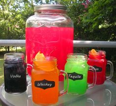 four different colored drinks sitting on top of a metal table next to eachother