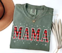 Spread the holiday cheer with this Plaid Mama Christmas Shirt! Perfect for moms, this stylish Comfort Colors T-shirt features a festive plaid "Mama" design surrounded by snowflakes. Whether you're enjoying a family Christmas gathering or shopping for holiday gifts, this shirt is a cozy, cheerful addition to your wardrobe. Makes a thoughtful and festive gift for moms who love the holidays! PRODUCT DESCRIPTION: Comfort Colors presents the "Comfort Colors 1717" t-shirt, a customizable, 100% ring-spun cotton garment. Soft-washed and garment-dyed, this relaxed-fit tee offers coziness and durability with double-needle stitching and seamless construction. Made with pre-shrunk, medium-weight 6.1 oz/yd² fabric, it ensures a consistently great fit. Available in 58 colors and proudly crafted using et Mama Design, Mama T Shirt, Mama Tee, Christmas Gathering, Mama Shirts, Comfort Colors Shirt, Christmas Gift For Her, Plaid Christmas, Christmas T Shirt