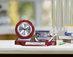 a red clock sitting on top of a desk next to a stack of books and a toothbrush