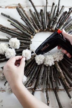 someone using a hair dryer to make a wreath out of sticks and yarns