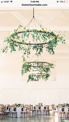 the tables are set up for an event with greenery hanging from the chandelier