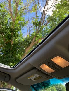 the inside of a car with trees and blue sky in the back ground, looking up at the sunroof