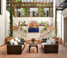 an indoor living room with couches and tables on the floor, surrounded by greenery