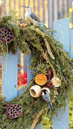 a wreath is hanging on the side of a wooden fence with birds and oranges