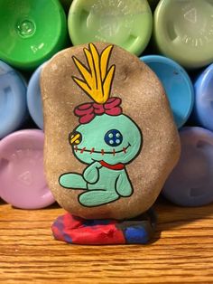 a rock with a cartoon character painted on it sitting in front of some colored rocks