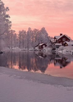 a lake with snow on the ground and houses in the background