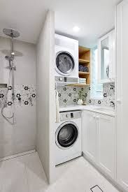 a washer and dryer in a white laundry room with tile flooring on the walls