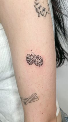 a woman with a tattoo on her arm holding a piece of fruit and two sticks