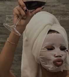 a woman with a towel on her head holding a glass of wine in front of her face