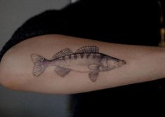 a woman's arm with a fish tattoo on it