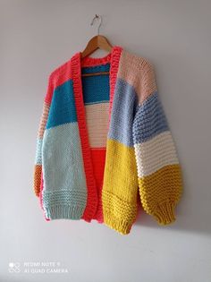 a multicolored sweater hanging on a white wall