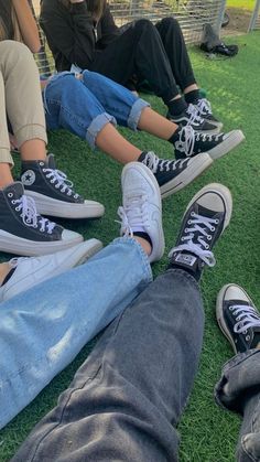 four people sitting on the grass with their feet up and one person wearing blue jeans