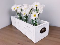 some white daisies are sitting in a wooden box