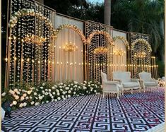 an outdoor wedding setup with white flowers and chandeliers on the wall, surrounded by greenery