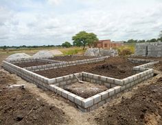 an unfinished brick wall in the middle of a field