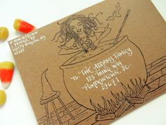 a card with a drawing of a witch in a caulder on top of a table