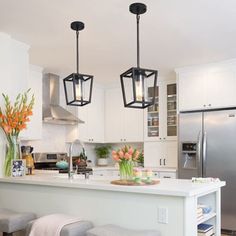 a kitchen with two pendant lights hanging over the island