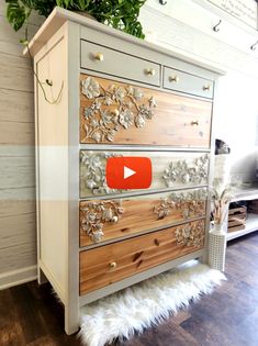 an old dresser has been decorated with flowers and leaves on the drawers, while a plant is